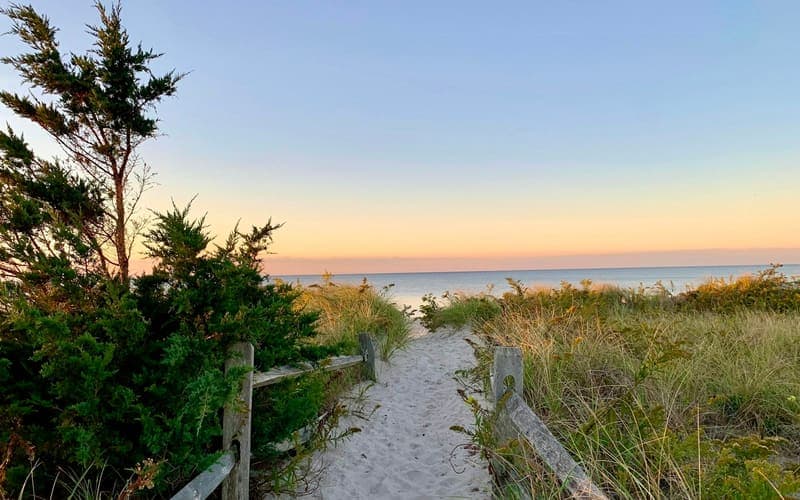 A sand path through dune grass down to the water at dusk on Cape Cod